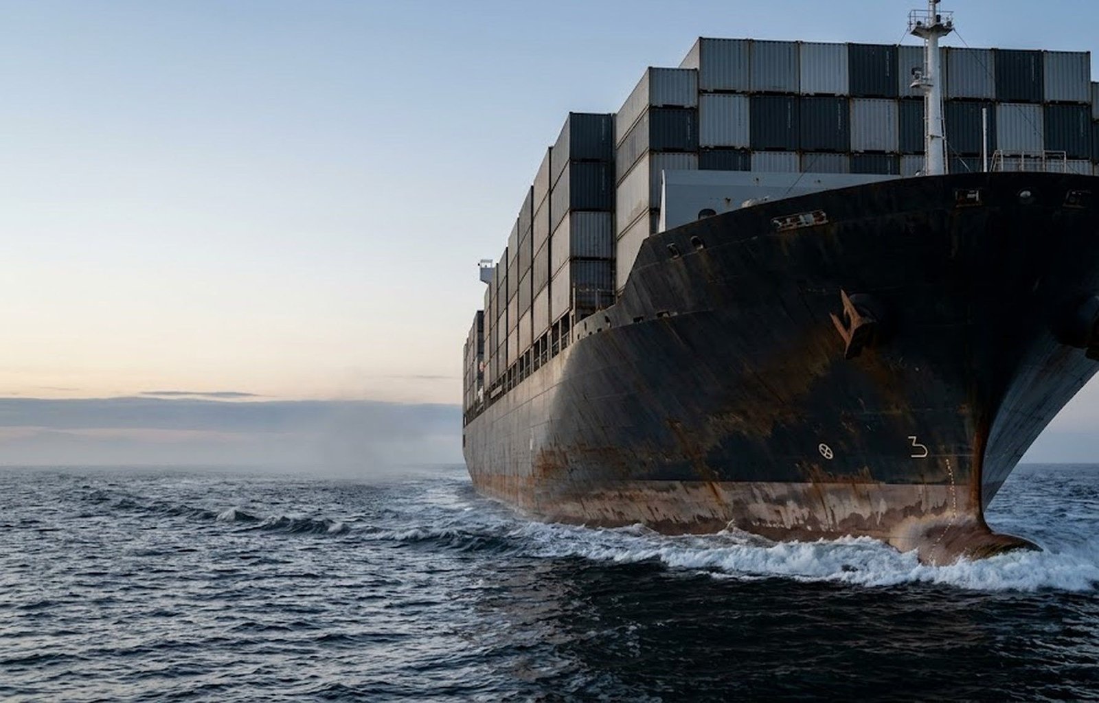 A loaded container ship under way at sea at first light.