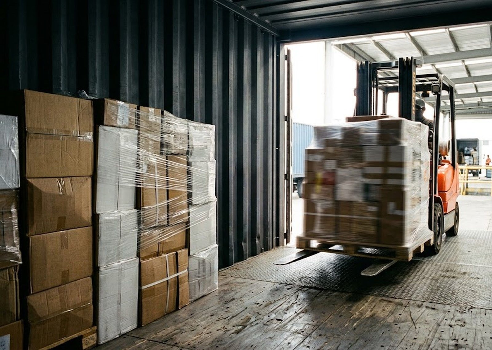 A forklift stuffing palletised cargo into a container at a consolidation warehouse.